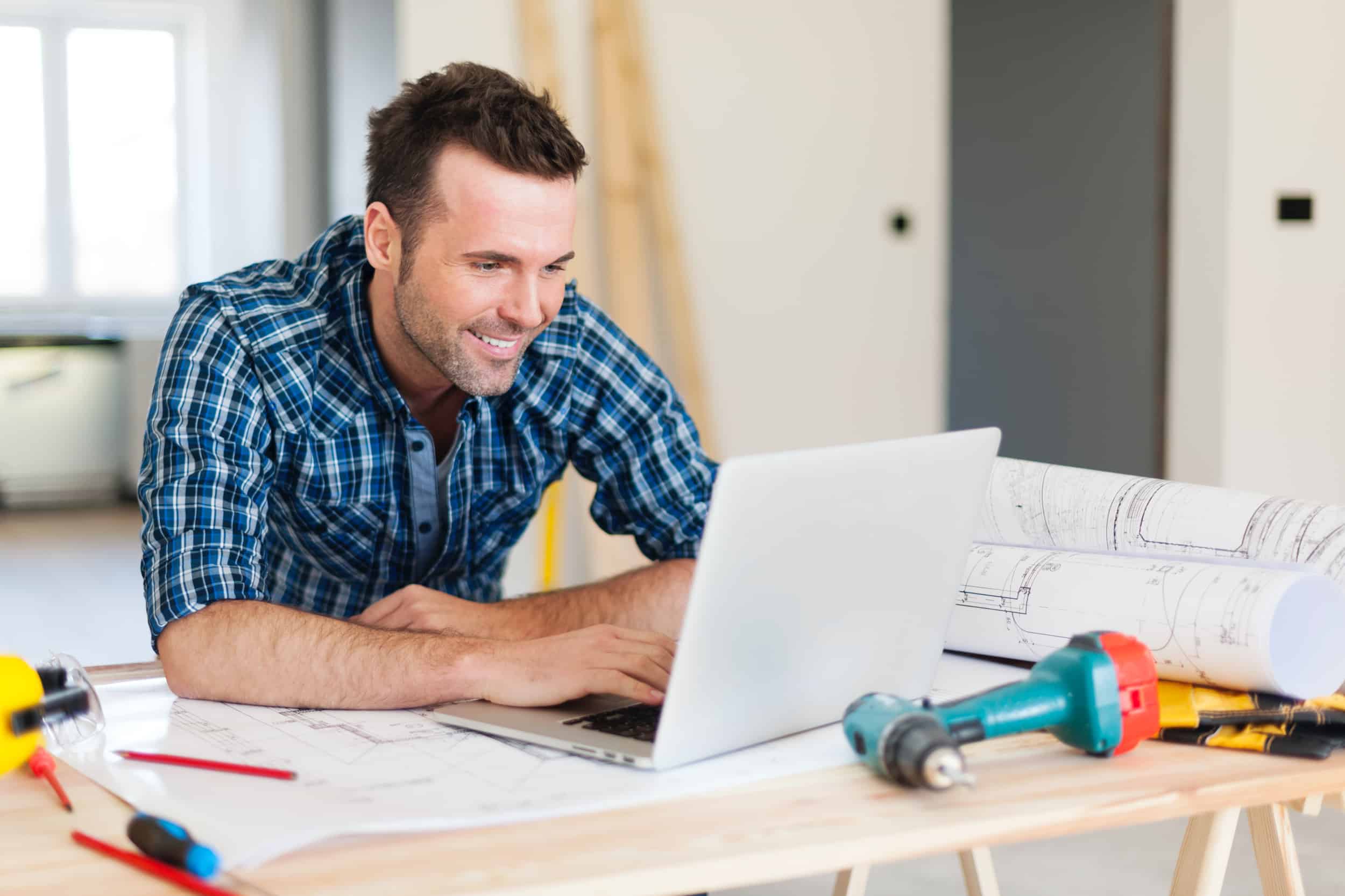 smiling-construction-worker-working-with-laptop-DBEML6Q_reach-company-business-website-marketing-and-seo-messaging